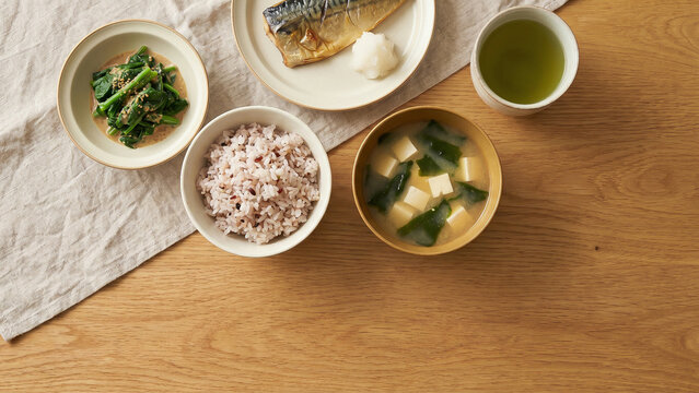 Sunlit Overhead View of Traditional Japanese Breakfast with Grilled Mackerel Rice Miso Soup and Green Tea Symbolizing Wellness Perfect for Advertising Menu Presentation and Food Background