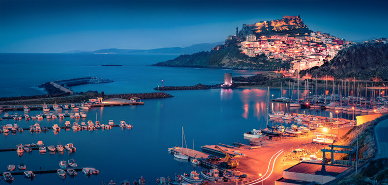 Сharm of the ancient cities of Europe. Panoramic night cityscape of Castelsardo port. Illuminated outdoor scene of Sardinia island, Province of Sassari, Italy, Europe. Aerial Mediterranean seascape.