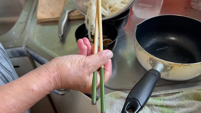 キッチンでうどんを作る高齢者