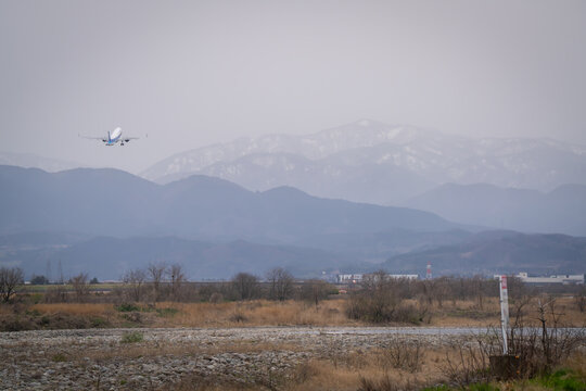 Airplane landing and take off at the airport in the city where we can see Japan alps background Toyama Japan 