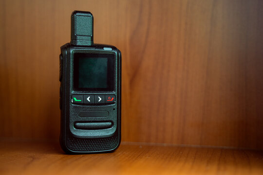 Small wireless walkie talkie mobile radio communication. Isolated by blurred wooden background. Technology concept.