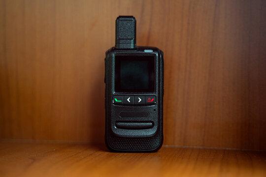 Small wireless walkie talkie mobile radio communication. Isolated by blurred wooden background. Technology concept.