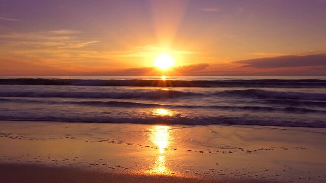 Golden sun setting over a tranquil ocean horizon with waves rolling onto a sandy beach shore, casting a bright reflection on the wet sand under a vibrant purple and orange sky.
