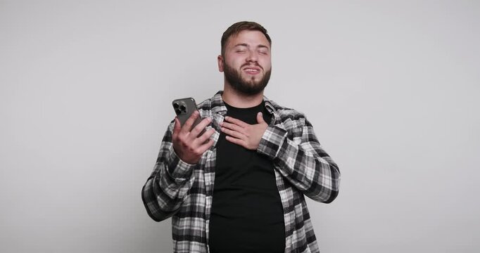 Man reacts to funny content on phone while smiling in a simple room at night