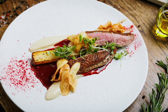 Gourmet duck meat with crispy vegetable chips and herbs