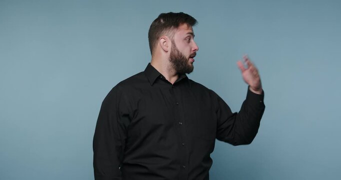 Man explains topics with gestures and clear speech while standing against a blue background