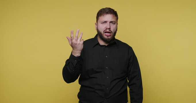 Man shows numbers using hands in a bright yellow background in a studio setting during daytime