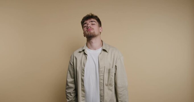 Young man plays on phone in multiple frames indoors with plain background and changes expressions