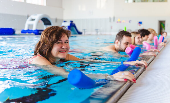 Group of people of various ages participating in an aqua aerobic class in an indoor swimming pool
