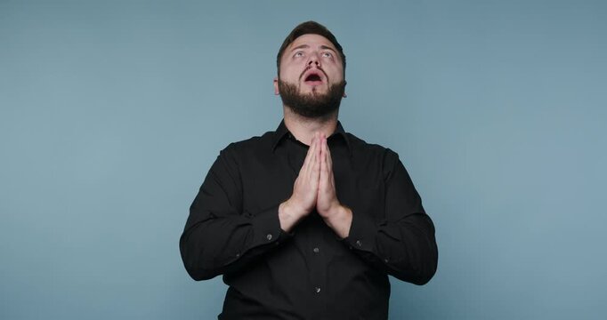 Person shows gratitude with hands together in front of their chest while smiling in a simple indoor setting during daytime