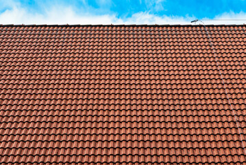 Naklejka premium Red ceramic roof tiles texture against blue sky