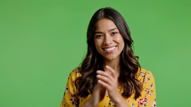 Happy young woman clapping hands and smiling on green screen background applause