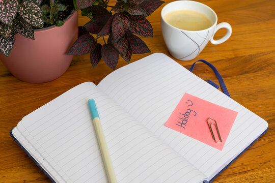 Carnet ouvert avec note vacances et tasse de caf&eacute; sur table en bois