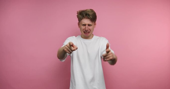 Man expresses strong feelings in front of pink background with hand gestures and intense facial expressions during daytime