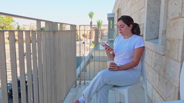 Woman using phone app on balcony overlooking historic town