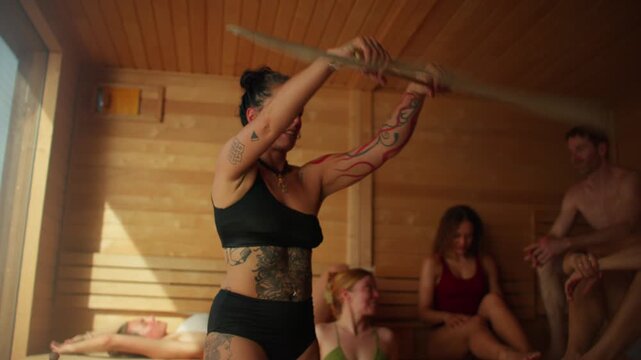 In a wooden spa, the sauna master guides a sauna aufguss ritual for a group