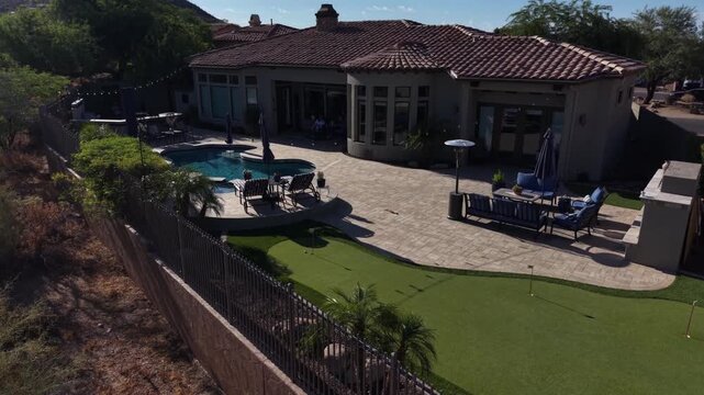 An aerial view of a desert landscaped backyard in Arizona, featuring a travertine pool deck with spa, outdoor BBQ and fireplace.