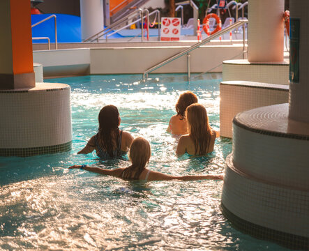 Group of happy women relaxing and talking in a hot tub of a modern indoor water park