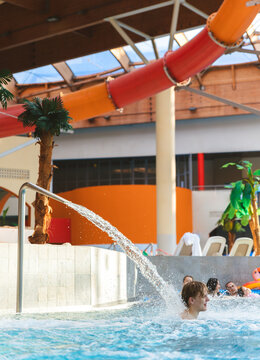 Young man enjoying water spray in an indoor swimming pool of a large water park