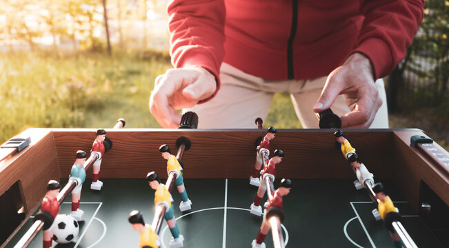 Man playing table football outdoors in a garden setting, capturing casual recreation as a gateway to the Football World Cup