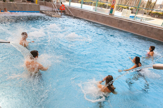 High angle view of a group of friends relaxing and enjoying water jets in a large indoor swimming pool at a water park