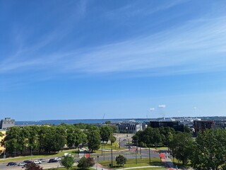 Obraz premium Tallinn, Estonia. View of a waterfront park with trees and buildings under a clear blue sky on a sunny day