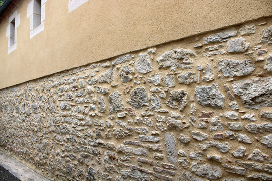Mur en pierre jointoy&eacute;e en soubassement, surmont&eacute; d&rsquo;une partie haute en cr&eacute;pi ocre
