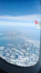 View from Airplane Window Above the Clouds © Thanchanok