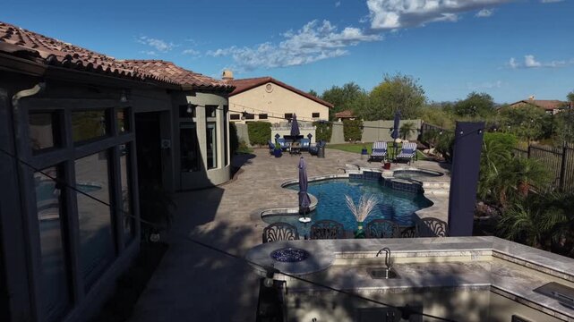 An aerial view of a desert landscaped backyard in Arizona, featuring a travertine pool deck with spa, outdoor BBQ and fireplace.