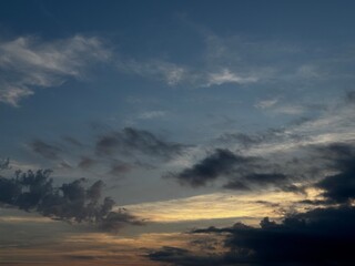Fototapeta premium Dramatic evening sky with dark clouds and soft golden sunset light. Atmospheric cloudscape background with moody weather, natural twilight colors and spacious copy space.
