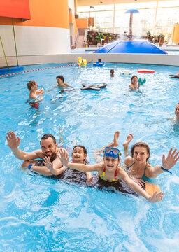 Portrait of a happy family smiling and looking at the camera while relaxing with pool floats at an indoor water park