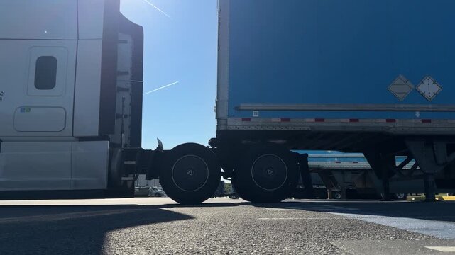 Semi-truck tractor coupling with a semi-trailer in a logistics yard.