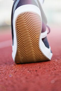 sneaker sole texture shoe bottom rubber tread zig zag pattern close up view of sneaker tread on running track looking away outdoor sports stadium concept of athletic gear, manufacturing