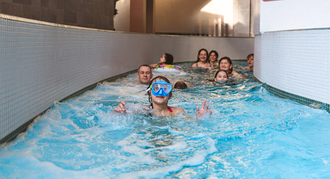 Happy family with children relaxing and swimming down a lazy river stream at an indoor water park