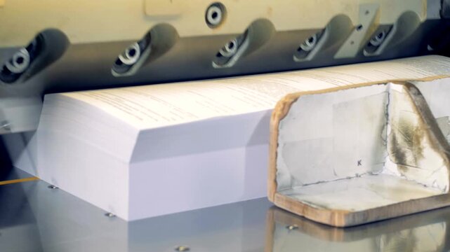 Industrial guillotine cutting stack of printed paper sheets