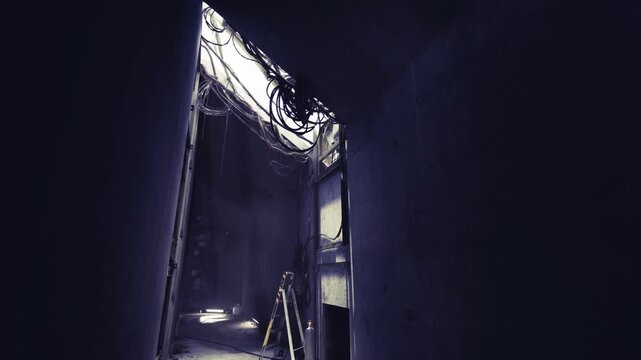 Service corridor prepared for electrical inspection, visible junction boxes and tangled cables, ladder positioned for access, utilitarian environment