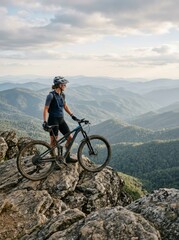 Fototapeta premium Cyclist standing on a rocky peak, mountain landscape.