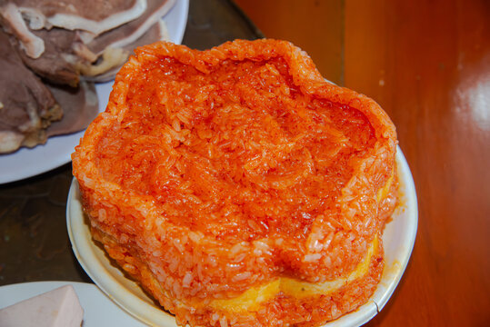 Close-up of Vietnamese xoi gac sticky rice with vivid orange color, served on a plate for Tet, festive food, and traditional Asian cuisine themes.