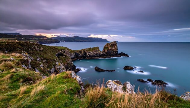 Coastal rocky outcrop at dusk with muted colors and smooth sea