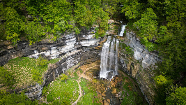 Aerial view of the Herisson waterfalls cascading down steep rocky cliffs surrounded by lush green forest in Menetrux-en-Joux, Bourgogne-Franche-Comte, France.