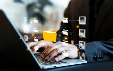 Businessman using laptop to manage digital document files and folders. Concept for cloud storage, data organization, database management, information technology, business automation, and connectivity. © wasan