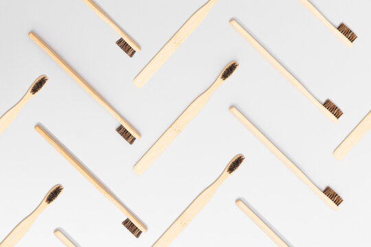 Geometric pattern of bamboo toothbrushes arranged in herringbone design on gray background