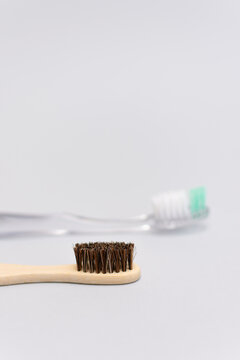 bamboo toothbrush in focus with blurred plastic toothbrush in background vertical composition