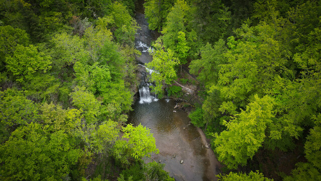 Aerial view of the Herisson waterfalls cascading through a lush green forest, Menetrux-en-Joux, Bourgogne-Franche-Comte, France.
