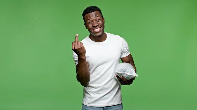 Young black man gesturing come here with hand holding package on green screen male
