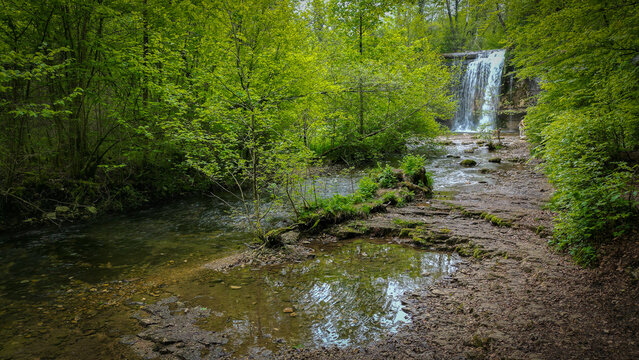 Aerial view of The Herisson waterfalls cascading into a rocky stream surrounded by lush green forest and dense foliage Menetrux-en-Joux, Bourgogne-Franche-Comte, France.