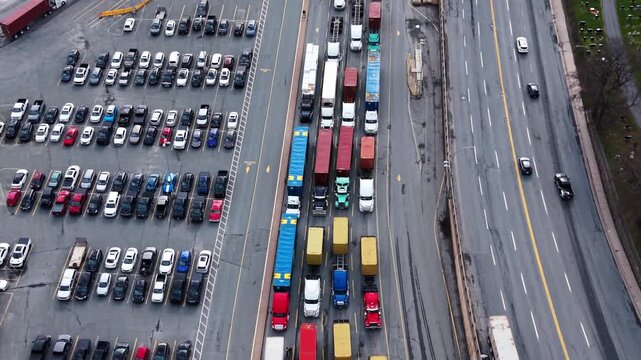 Semi-trailer trucks line up in a long queue at the Port of Halifax, showcasing the bustling activity of this important shipping hub in Canada