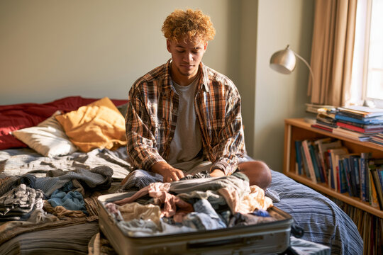 College student packing a suitcase in a dorm room or bedroom, representing moving out, student life, travel preparation and the transition to independent living