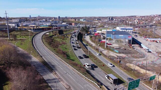 A bustling traffic intersection in Halifax, Nova Scotia, where vehicles stream toward a bridge amidst a clear blue sky and vibrant cityscape