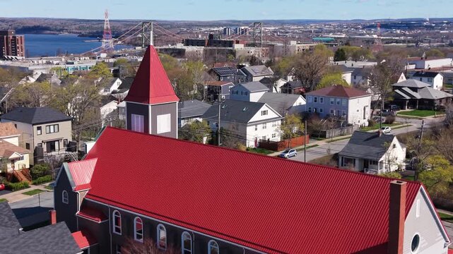 Witness the breathtaking aerial views of St. Stephen Church surrounded by charming homes and the beautiful Halifax waterfront, showcasing the city's unique character